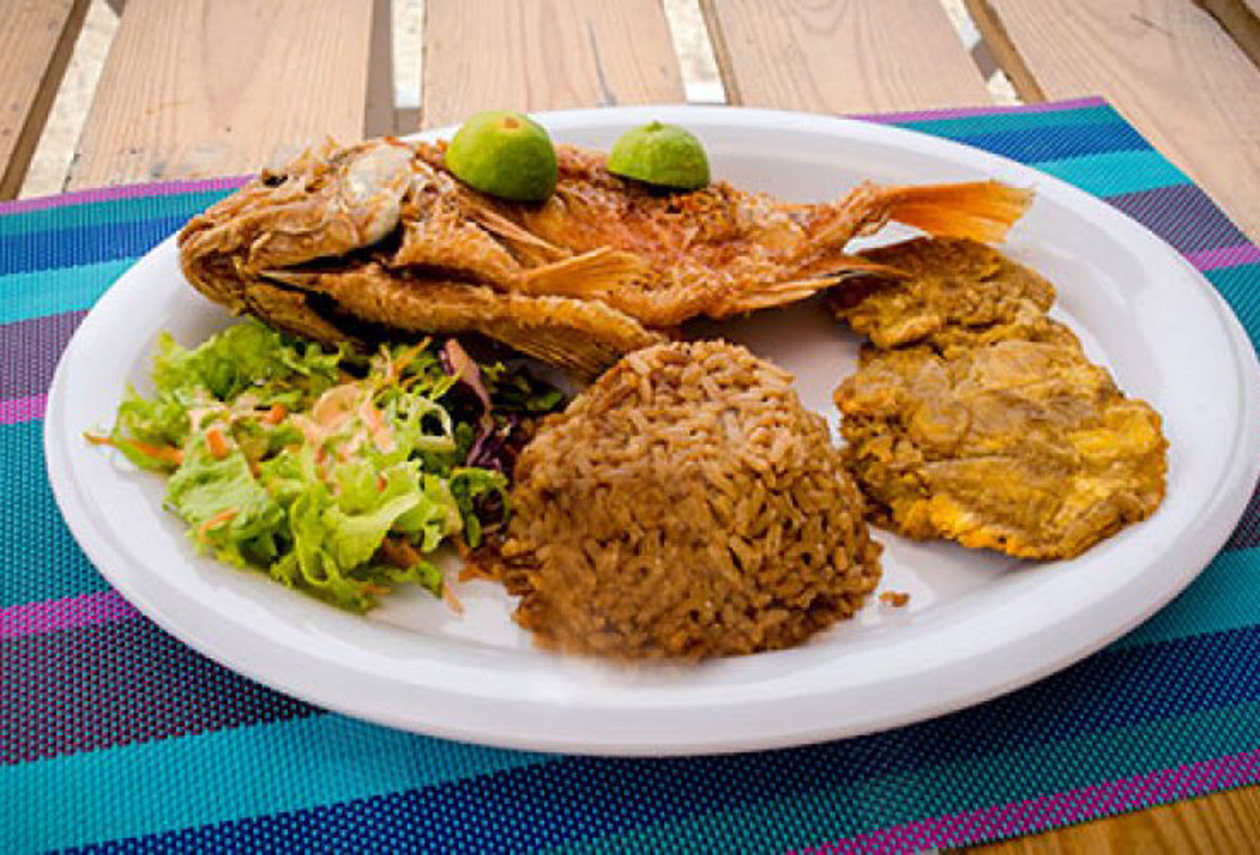Fourth slide: image d'un repas de poisson frite, riz du coco et platain vert et salade